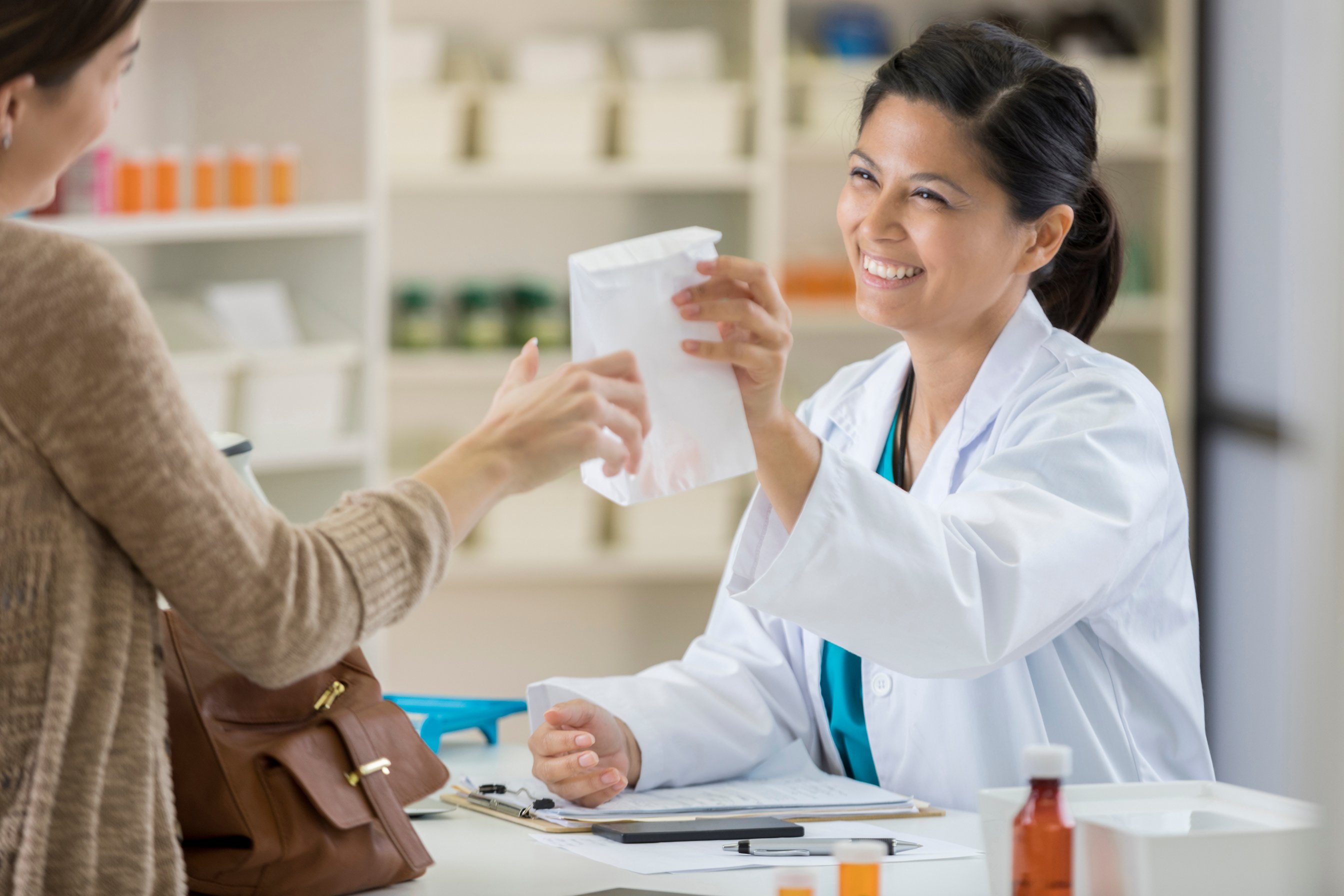 Beautiful Asian female pharmacist assists customer